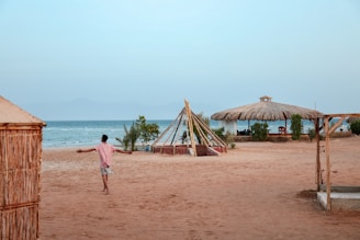 man wearing pink shirt walking on the seashore