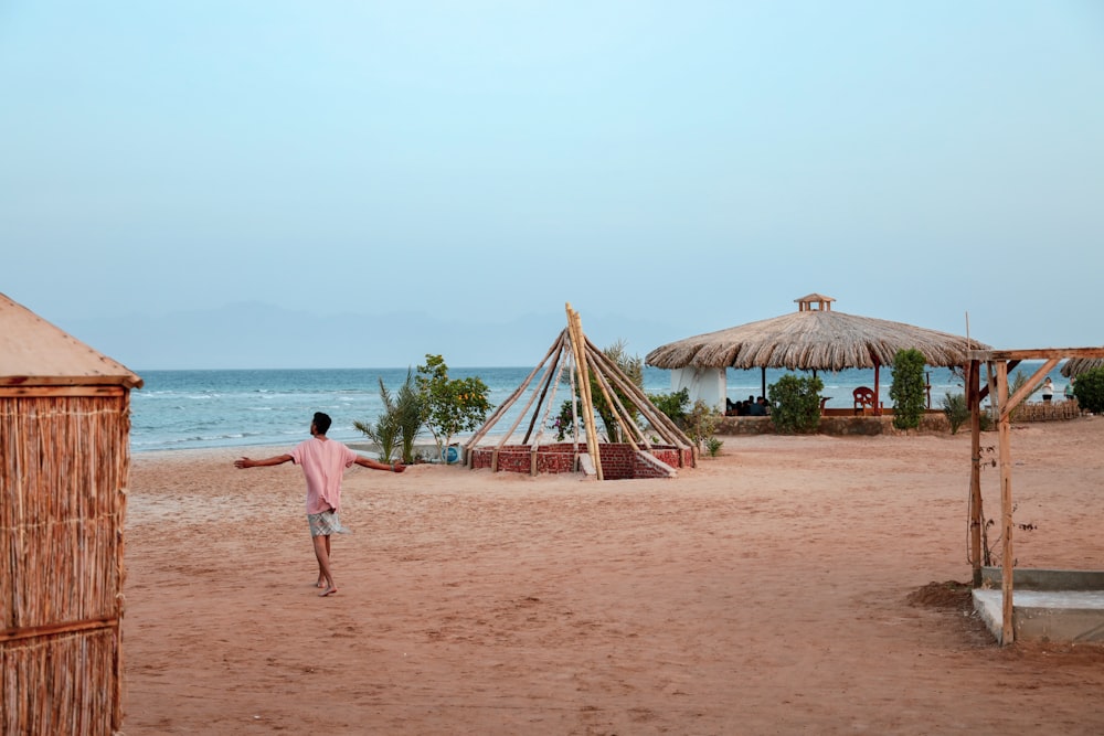 분홍색 셔츠를 입은 남자가 해변을 걷고 있다.