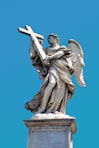 angel holding cross statue during day