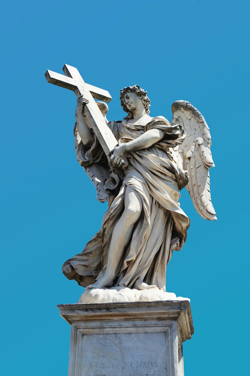 angel holding cross statue during day