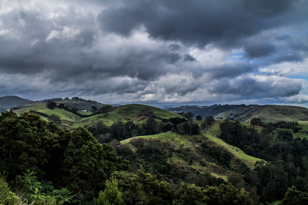 green field and mountain under gray and black skies