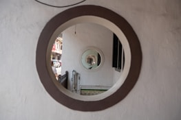 Concentric circles formed by round windows or mirrors create a tunnel-like visual effect, with a glimpse of an outdoor street scene visible through the openings.