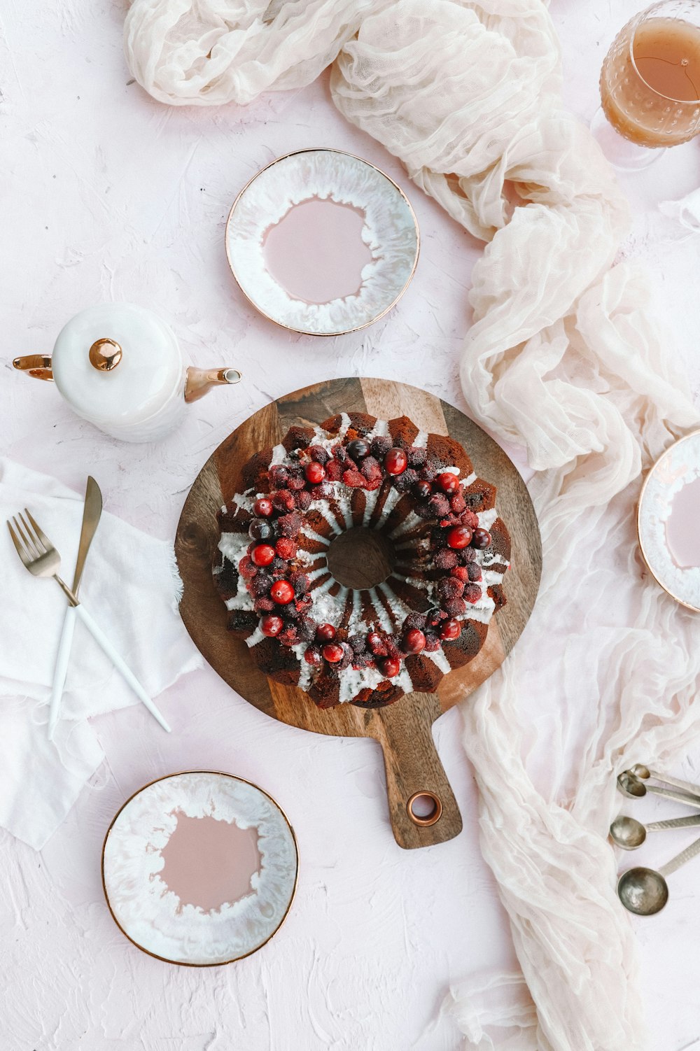 round cake beside teapot, fork and knife, on table