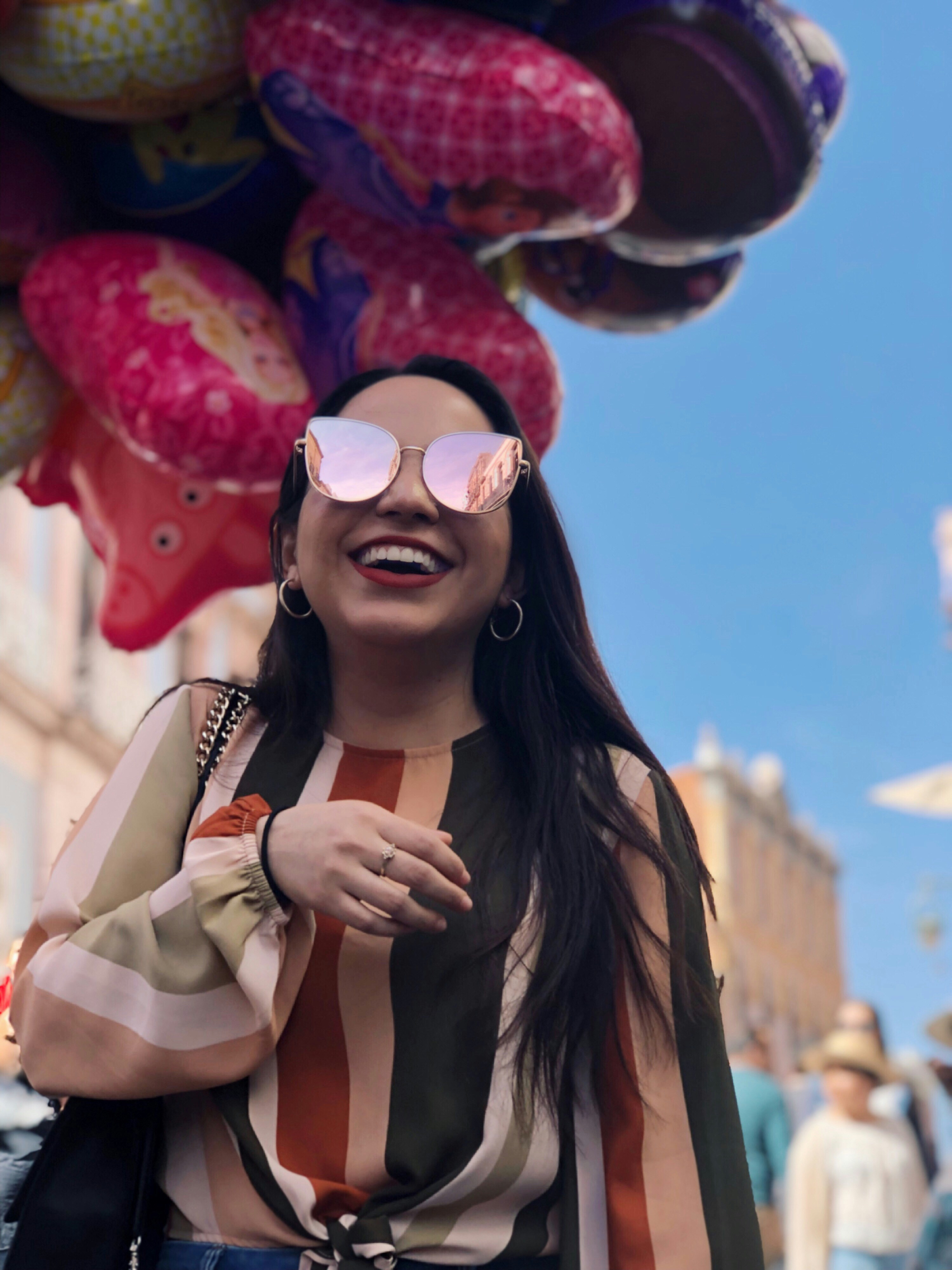 Femme souriante portant des lunettes de soleil debout à côté de ballons