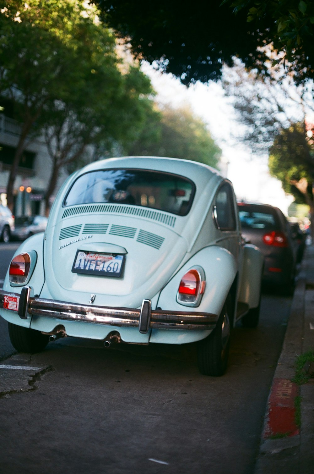 blue classic Volkswagen Beetle parked on side of road