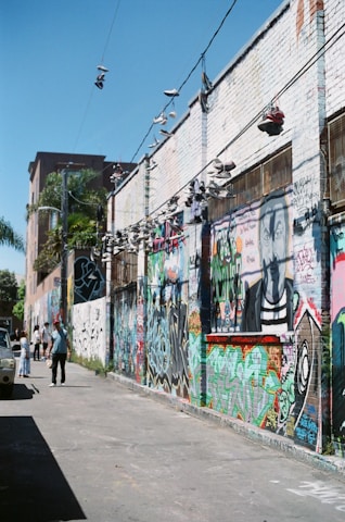 Urban street art wall with vibrant graffiti featuring Nike, Jordan, and Travis sneakers.