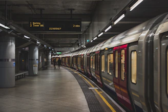 A London Underground train at a platform with a digital arrival sign