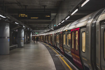A London Underground train at a platform with a digital arrival sign