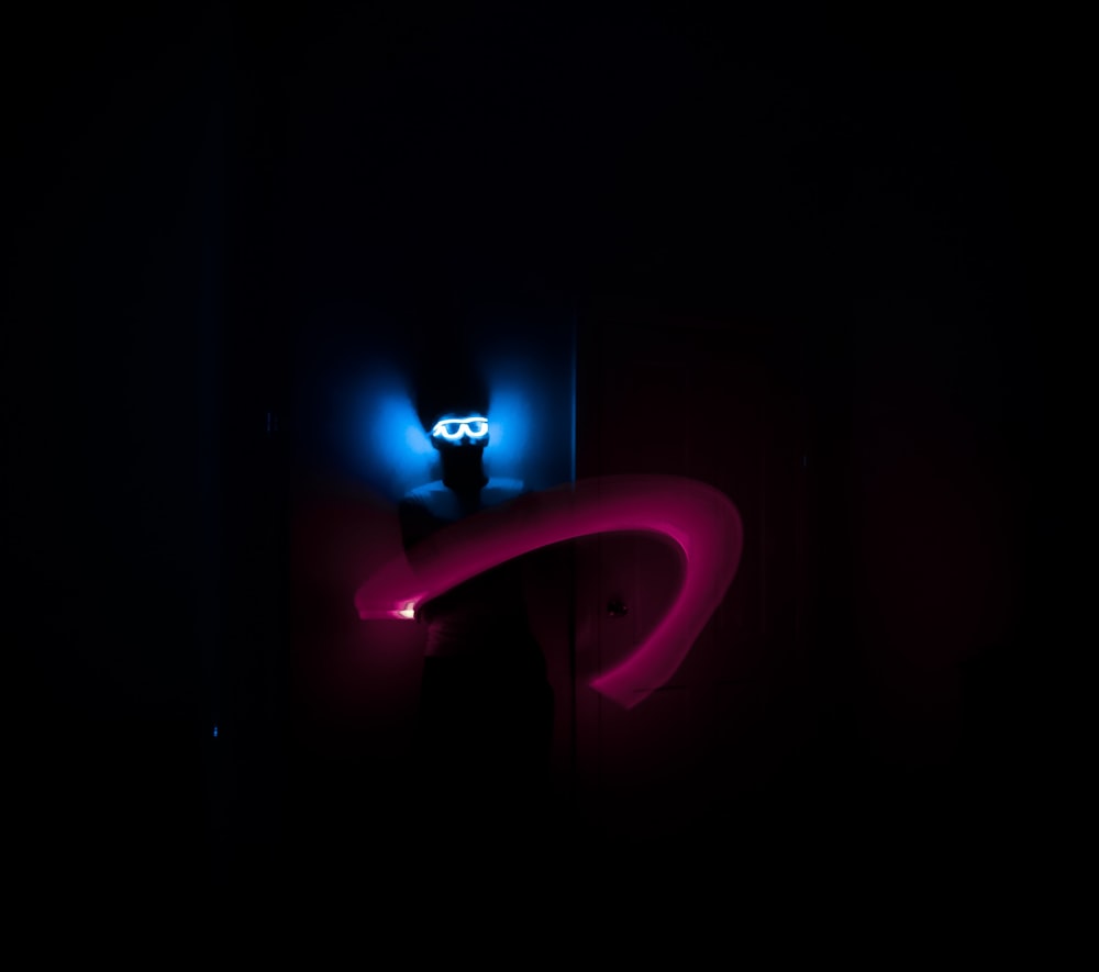 a person standing in a dark room with a neon light