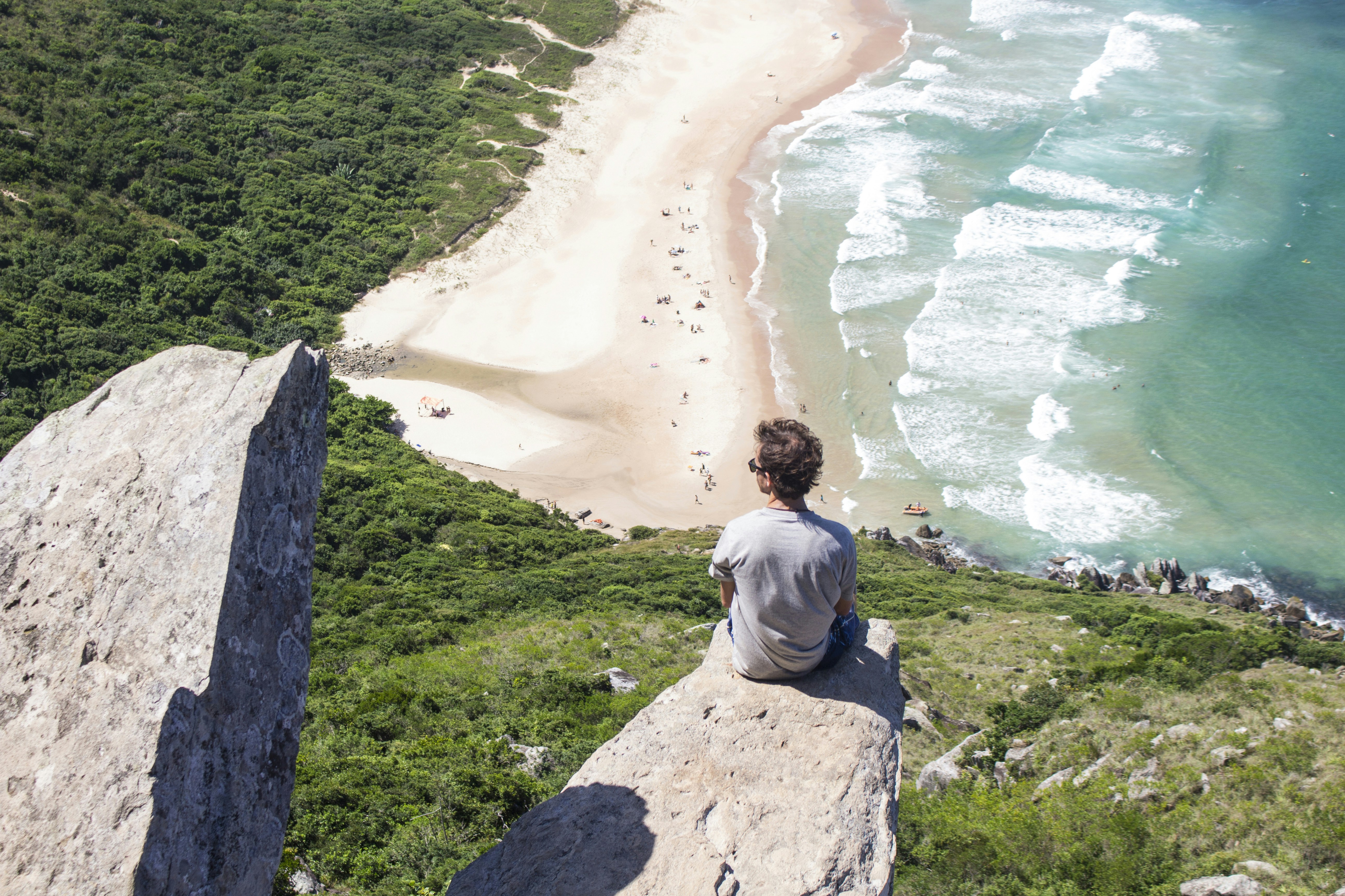 man sitting on gray rock