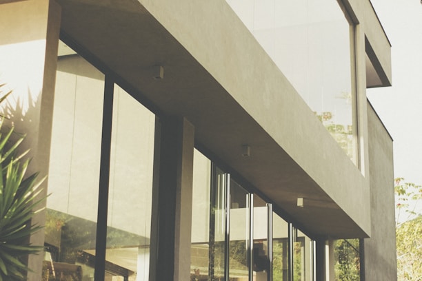 Modern architectural office building with large glass windows and greenery around.