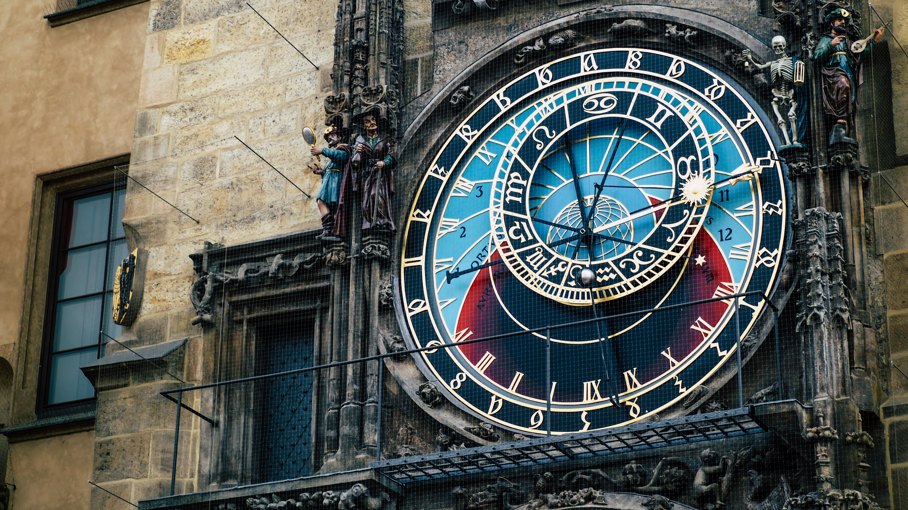 Close-up of the Prague Astronomical Clock, its blue and gold astrolabe dial and carved stonework set into the Old Town Hall wall