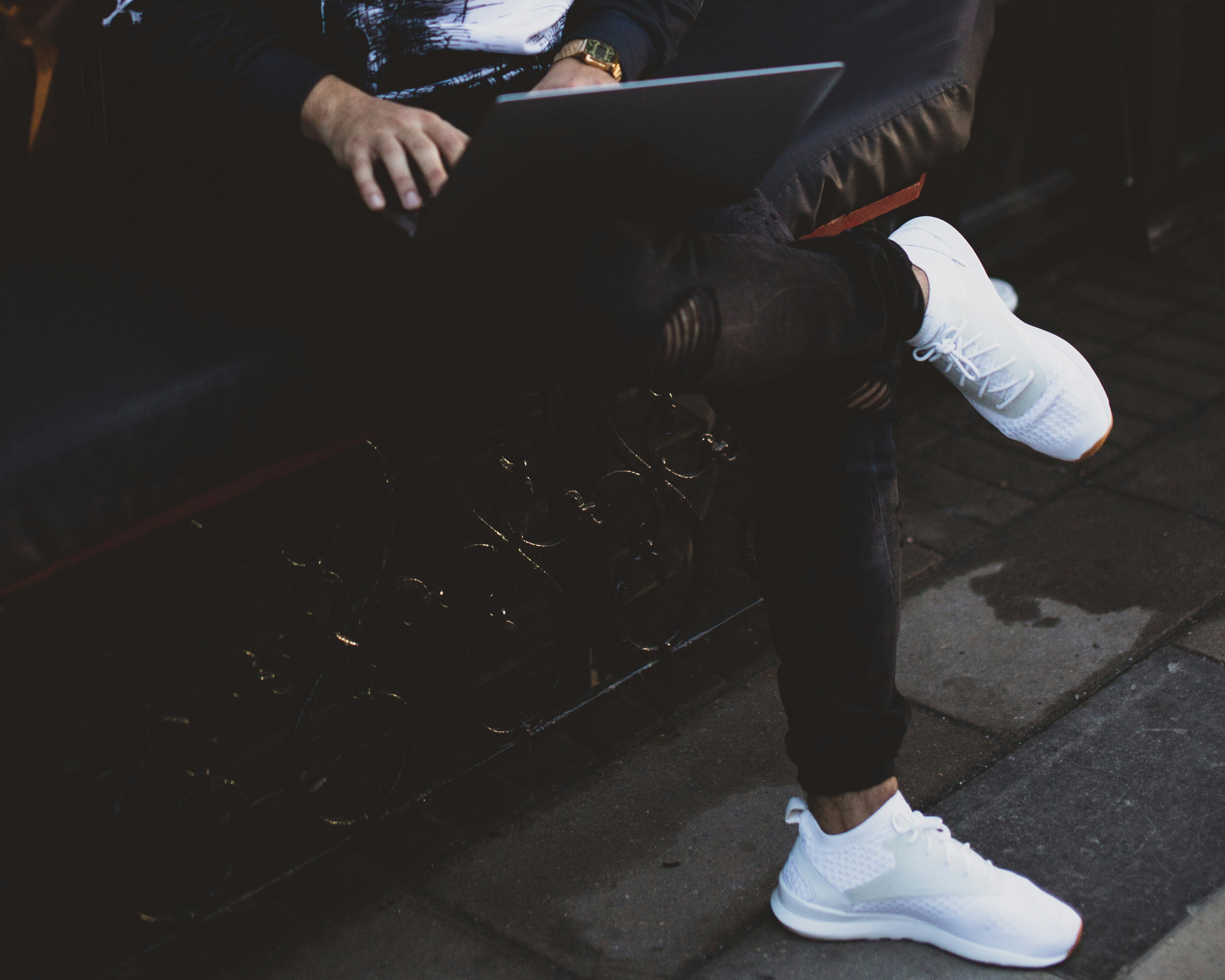 person wearing black denim pants using MacBook