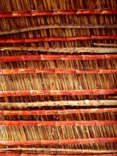 An arrangement of parallel bamboo sticks reinforced with horizontal wooden slats. The bamboo appears aged with natural imperfections, while the wood has a reddish-brown hue, creating an earthy texture.