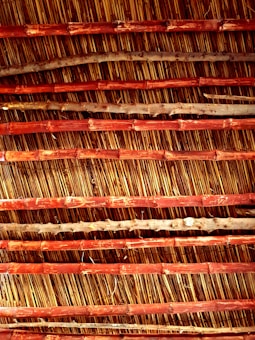 An arrangement of parallel bamboo sticks reinforced with horizontal wooden slats. The bamboo appears aged with natural imperfections, while the wood has a reddish-brown hue, creating an earthy texture.