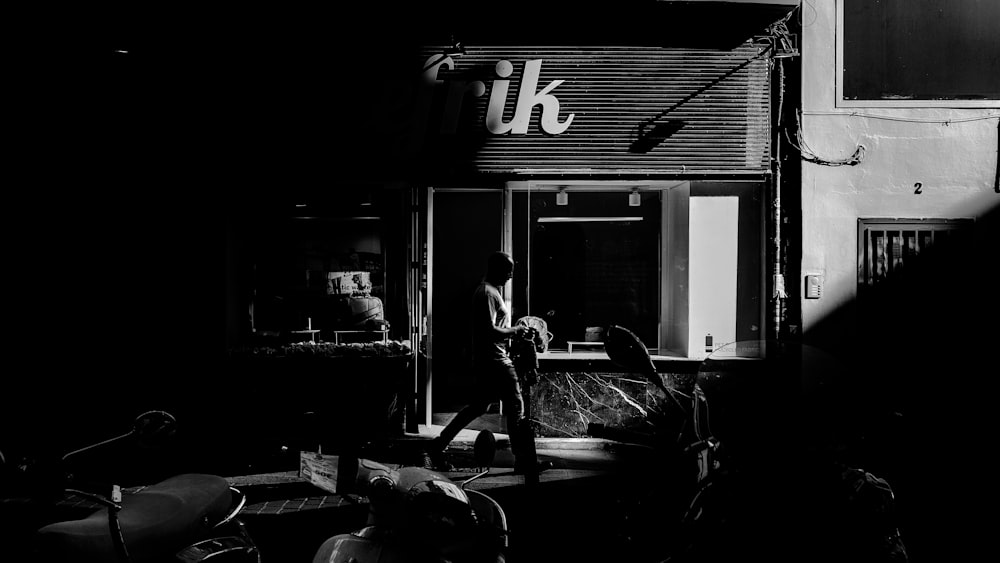 silhouette of man standing near wall in grayscale photo