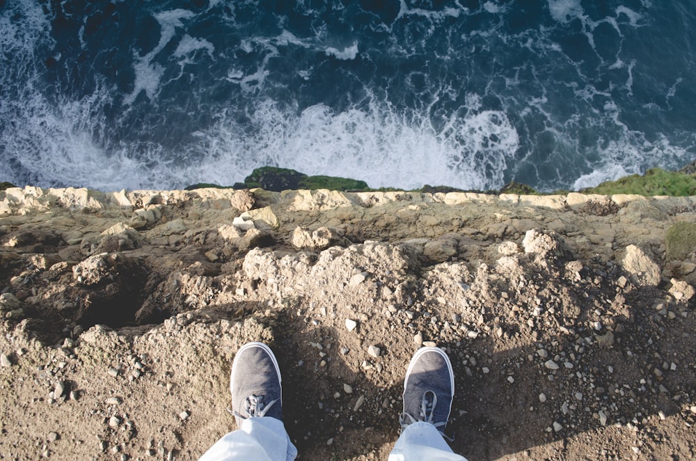 person standing on sea cliff during daytime