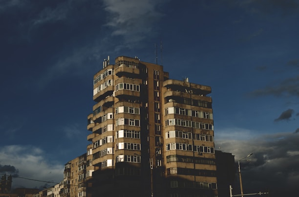 Aerial drone shot capturing a sleek, dark luxury apartment building in Bogotá at dusk.