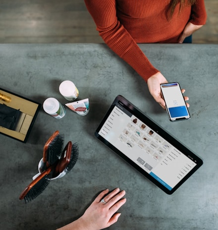 person holding smartphone beside tablet computer