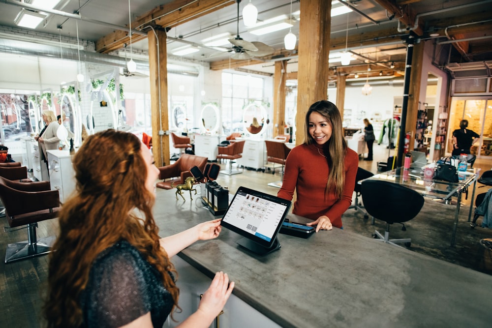 two people performing a transaction at a counter on either side of a point of sale system in a trendy salon