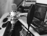 Close-up of a microphone with a pop filter in a modern recording studio setting.
