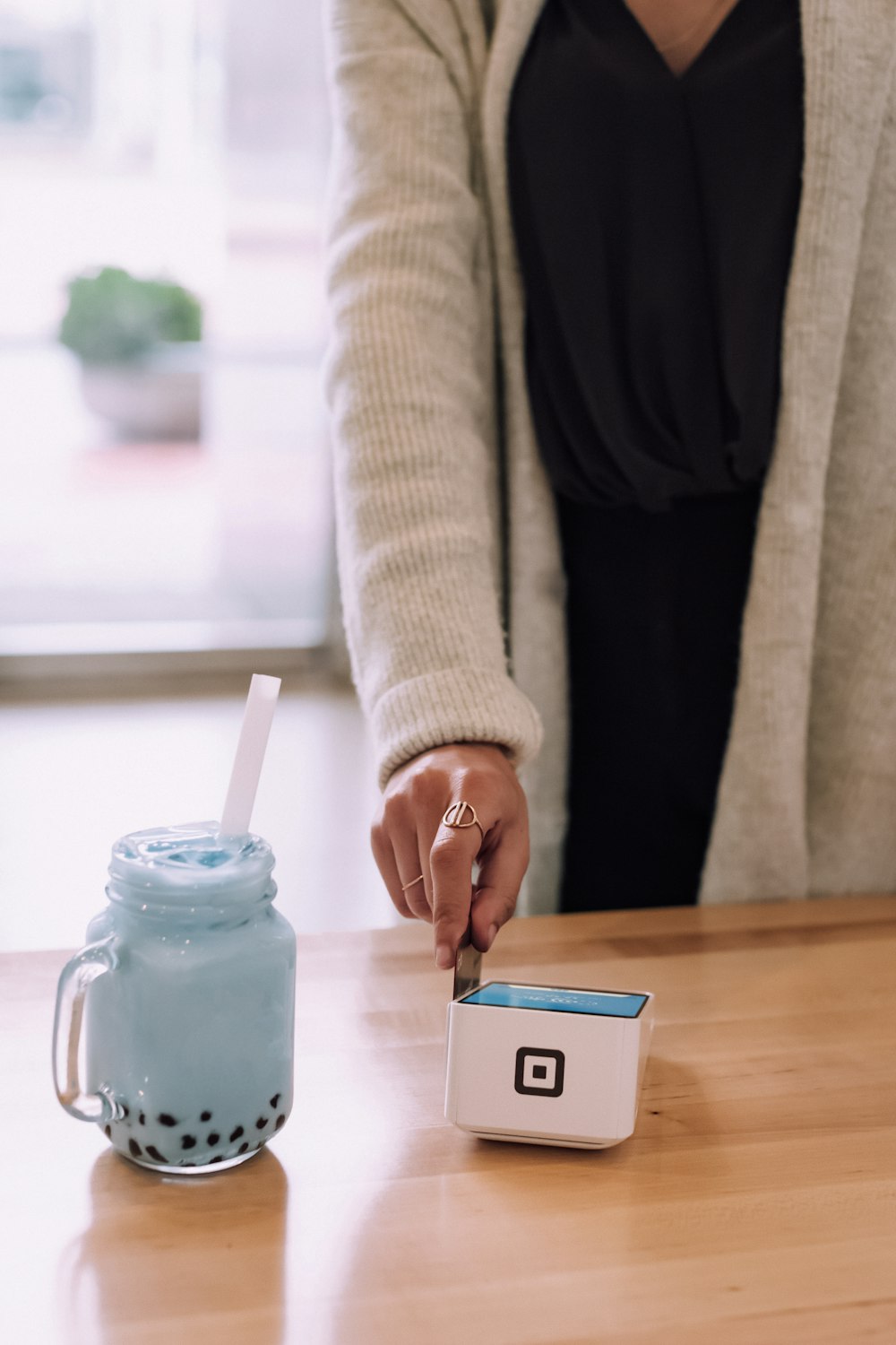 person in gray jacket holding device on table