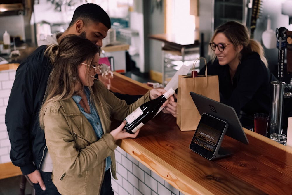 mulher segurando garrafa de vinho ao lado do homem na frente da mulher sorrindo