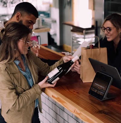 woman holding wine bottle beside man in front of woman smiling