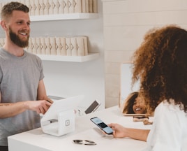 man in grey crew-neck t-shirt smiling to woman on counter