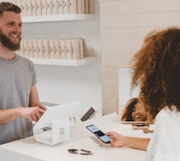 man in grey crew-neck t-shirt smiling to woman on counter