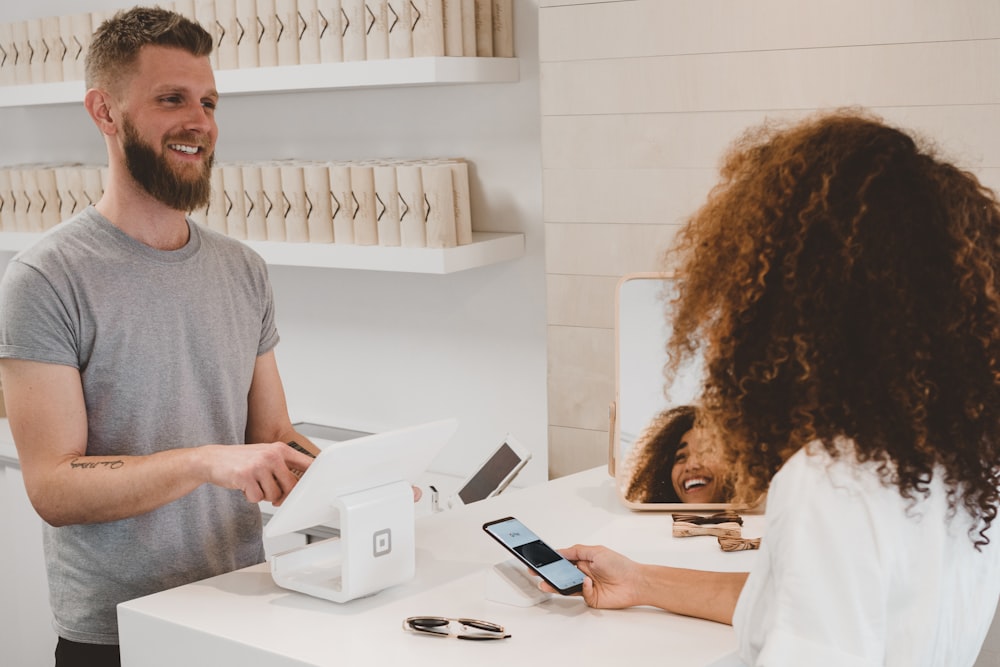 man in grey crew-neck t-shirt smiling to woman on counter - customer loyalty program
