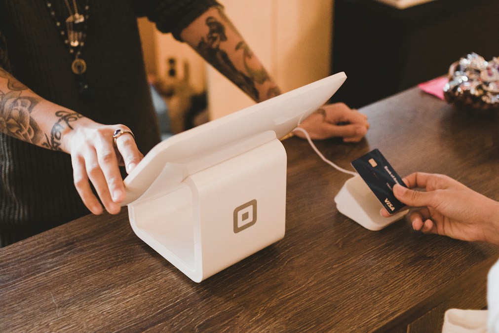 Terminal de paiement blanc sur le comptoir d'une boutique, un client tend sa carte au vendeur (photo d'illustration, il ne s'agit pas d'un terminal Ecobank)