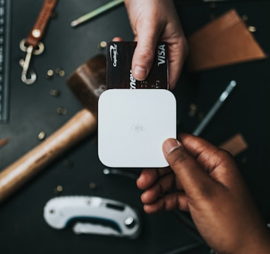 person holding Visa card and white device