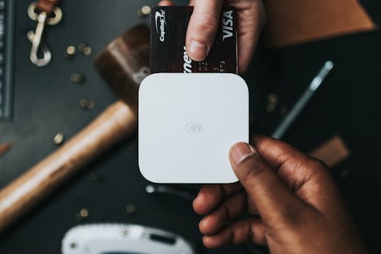 person holding Visa card and white device