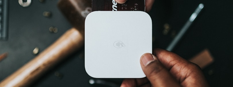 person holding Visa card and white device