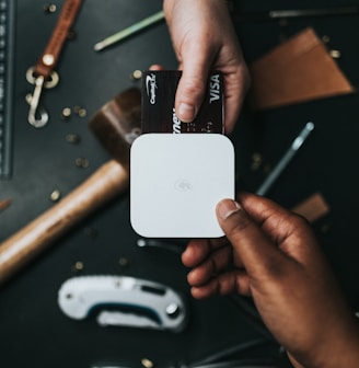 person holding Visa card and white device