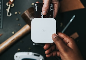 person holding Visa card and white device