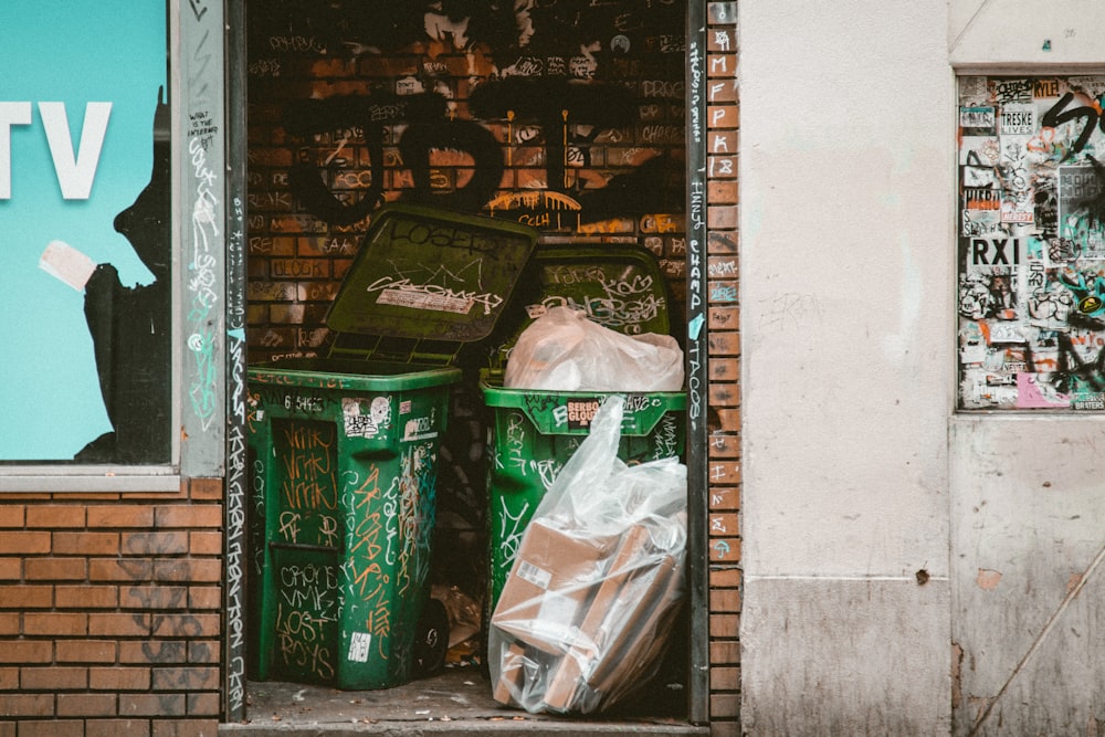 green dumpsters between brick walls