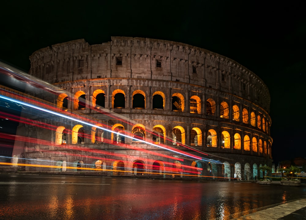 Coliseo de Roma de noche con estelas de luces en la calle