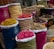 Colorful fabric bags and woven baskets display a variety of dried flowers and spices. The containers are filled with different colors and textures, showcasing ingredients like dried petals and herbs. Each bag is decorated with floral embroidery, enhancing the aesthetic presentation.