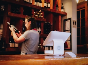 A friendly sommelier advising a customer inside the warmly lit wine shop.