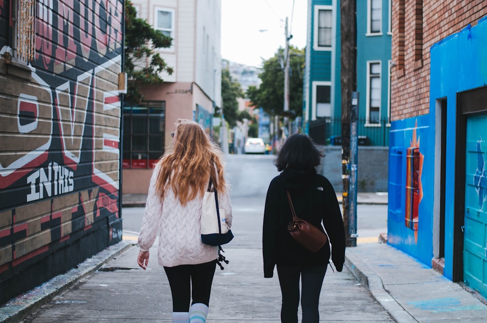 two women in sweaters walking on street