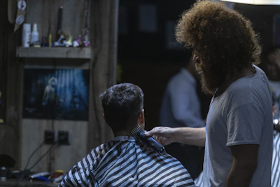 Barber giving a precise haircut in a sleek dark interior with golden accents.
