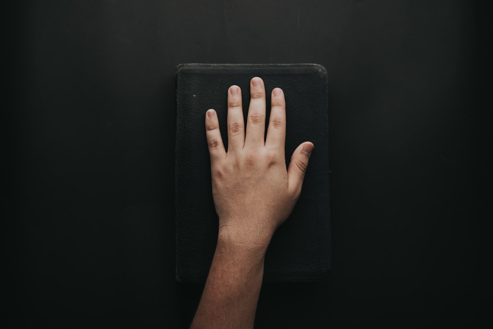 left human hand on black book