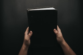 person holding closed black book von Luis Quintero (@jibarox)
