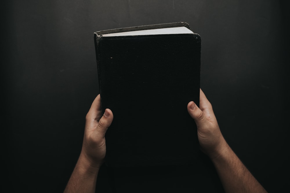 person holding closed black book