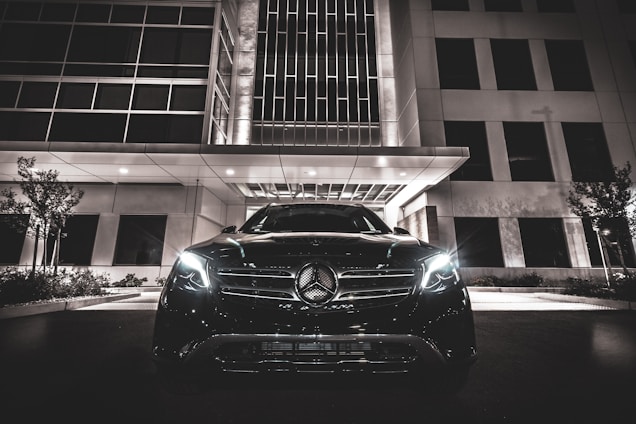 A sleek VIP taxi car waiting outside a modern building at night.