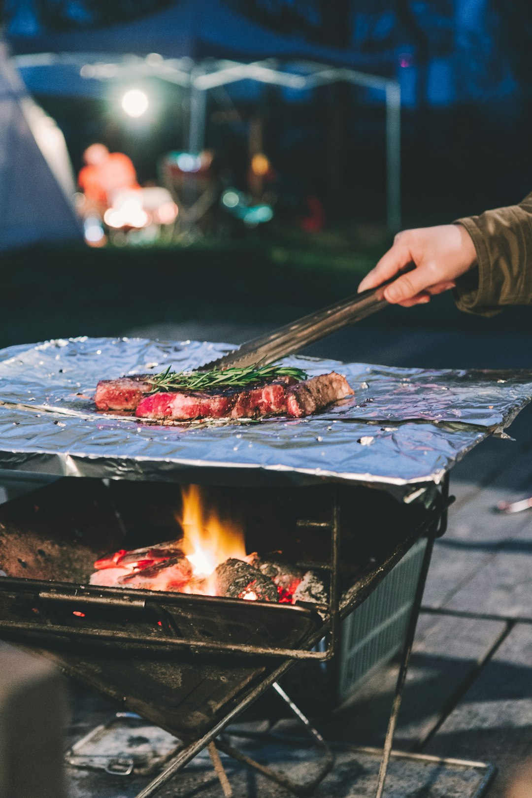 person grilling meat during daytime