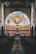 Interior of a church featuring a large, ornate mural depicting a religious scene with figures in a semi-circle, centered around a prominent seated figure, likely representing Jesus. The mural is positioned above an altar with a simple, symmetrical design. Rows of wooden pews fill the foreground, with a reflective marble floor capturing the image of the mural and altar. The setting is illuminated by hanging lights from a high ceiling.