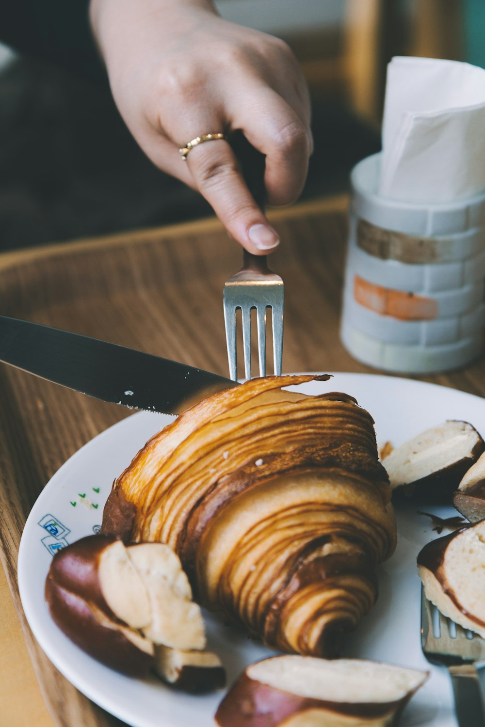 person wearing gold-colored ring slicing pastry on plate